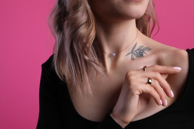 Photo of Beautiful woman with tattoo on body against pink background, closeup