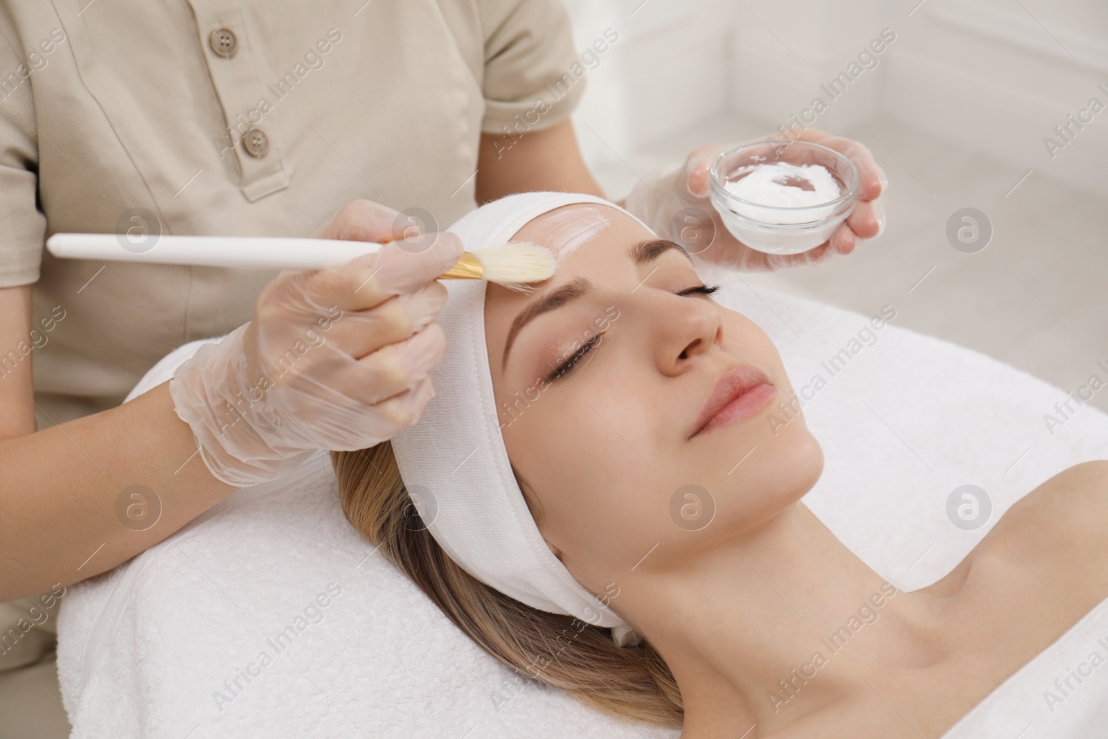 Photo of Young woman during face peeling procedure in salon