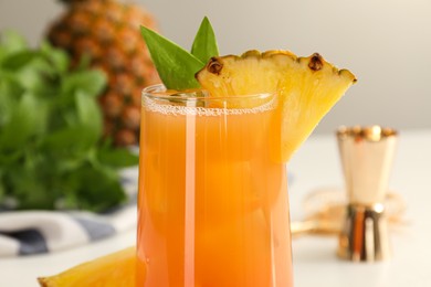Photo of Tasty pineapple cocktail in glass on table, closeup view