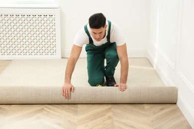 Photo of Worker rolling out new carpet in room