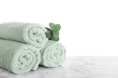 Fresh towels and eucalyptus branch on marble table against white background. Space for text