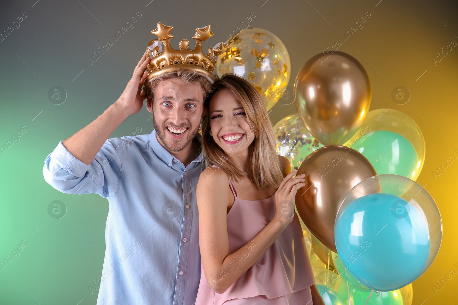 Photo of Young couple with air balloons on color background