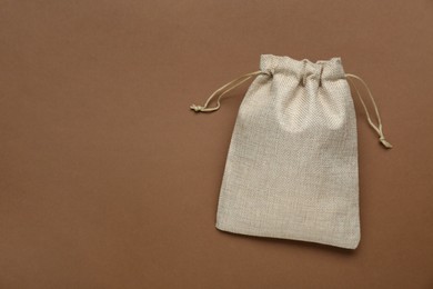 Photo of Burlap bag on brown background, top view. Space for text