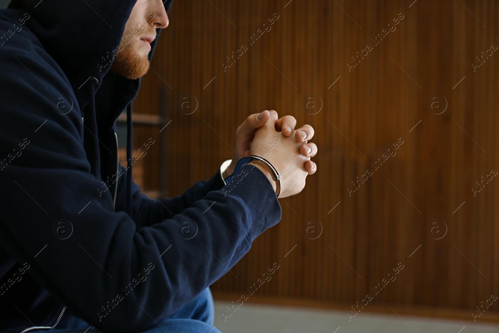 Photo of Man detained in handcuffs indoors, space for text. Criminal law