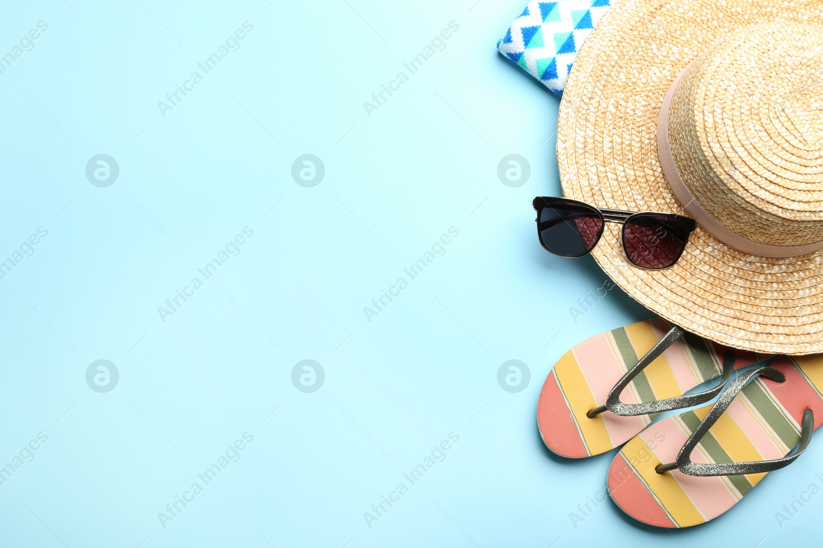 Photo of Beach accessories on light blue background, flat lay. Space for text