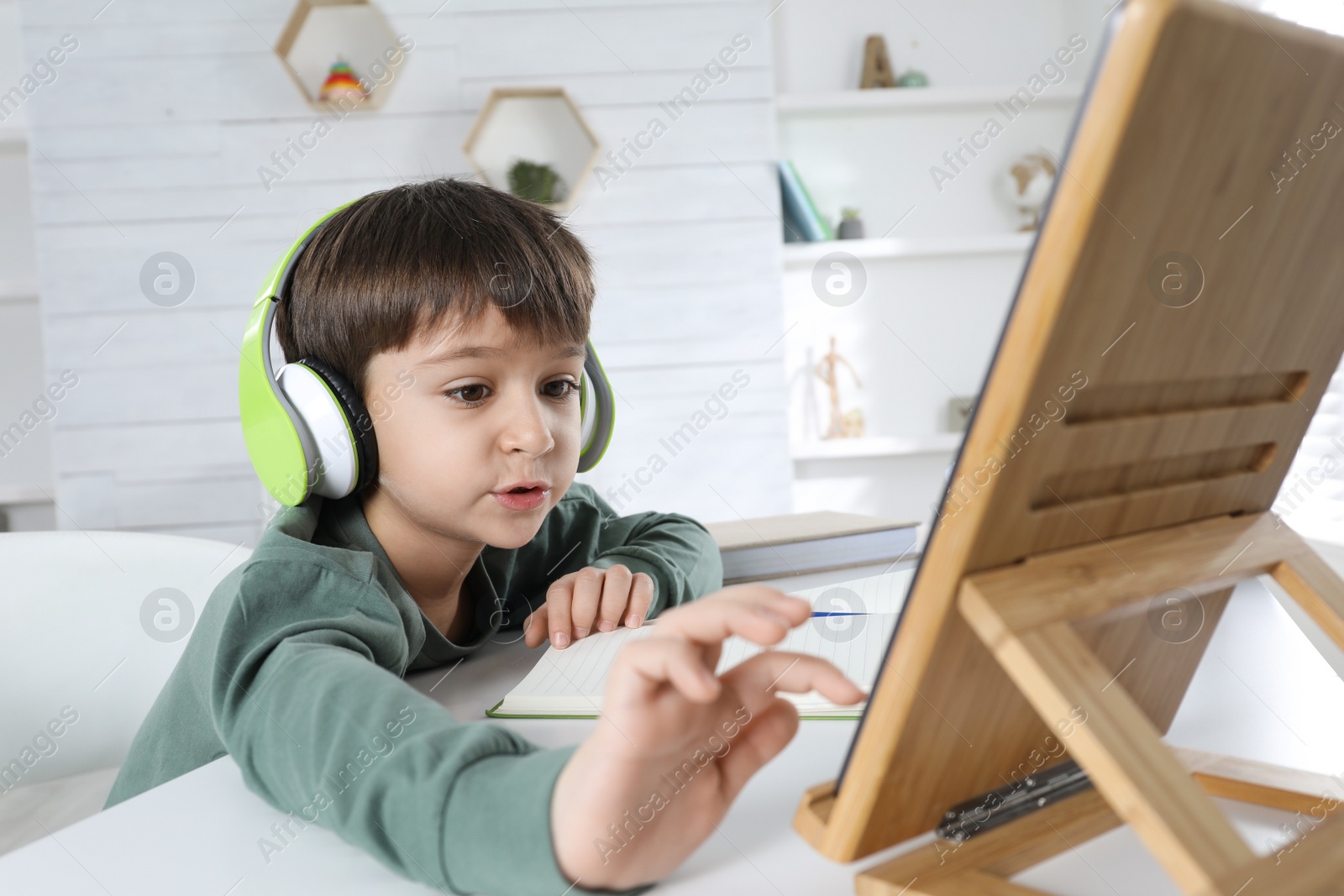 Photo of Cute little boy with modern tablet studying online at home. E-learning