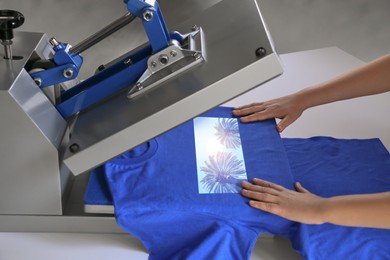 Custom t-shirt. Woman using heat press to print image of beautiful tropical palm trees, closeup