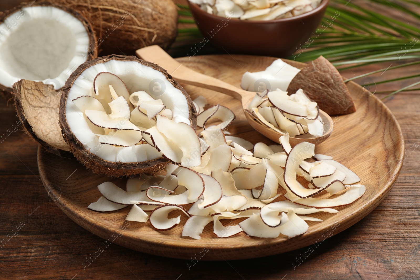 Photo of Composition with tasty coconut chips on wooden table