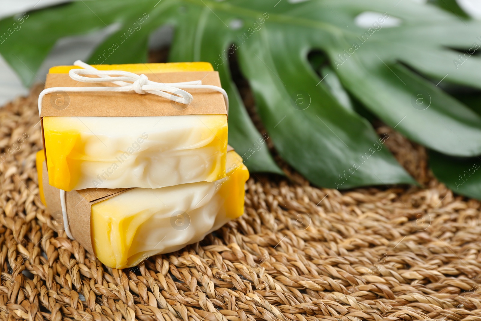 Photo of Natural handmade soap bars on wicker mat, closeup. Space for text