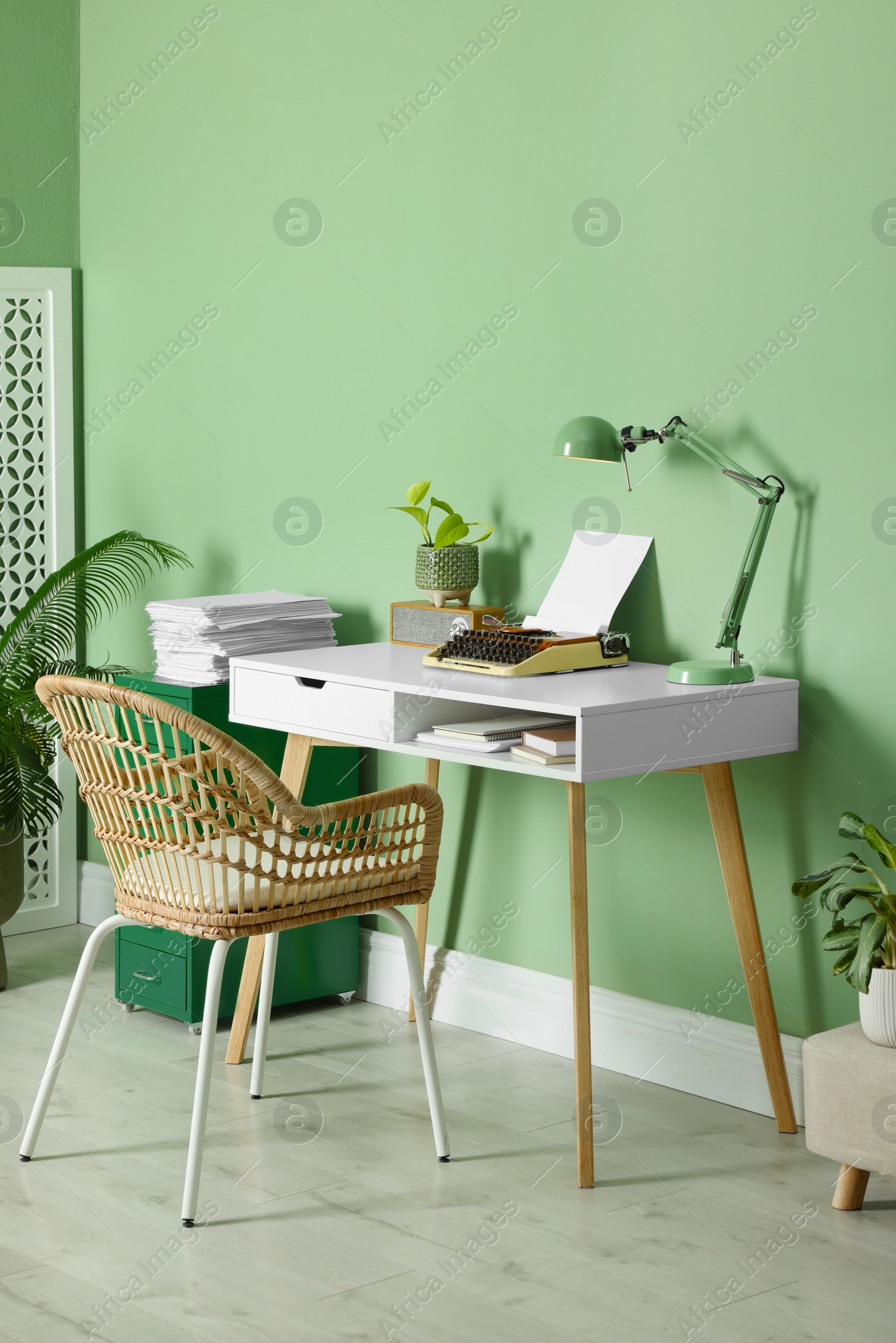 Photo of Writer's workplace with typewriter on wooden desk near pale green wall in room