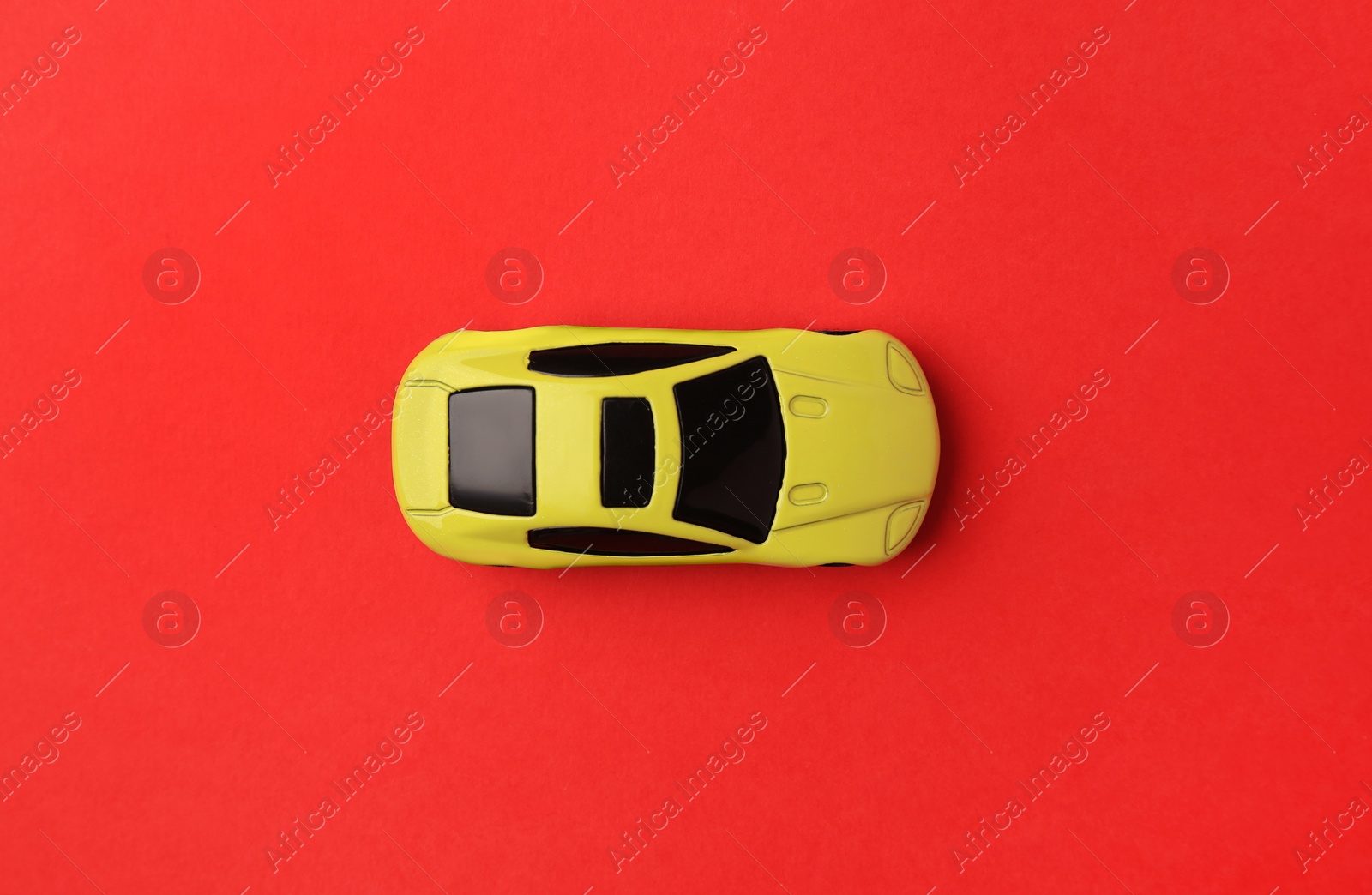 Photo of One yellow car on red background, top view