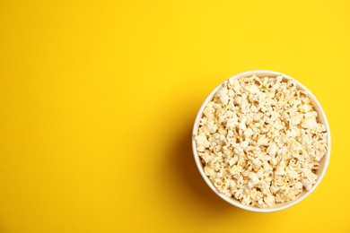 Paper bucket with tasty fresh popcorn on color background, top view