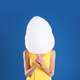 Photo of Young woman with cotton candy on blue background