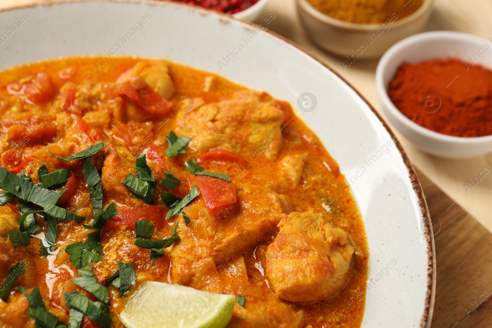 Photo of Delicious chicken curry and spices on table, closeup
