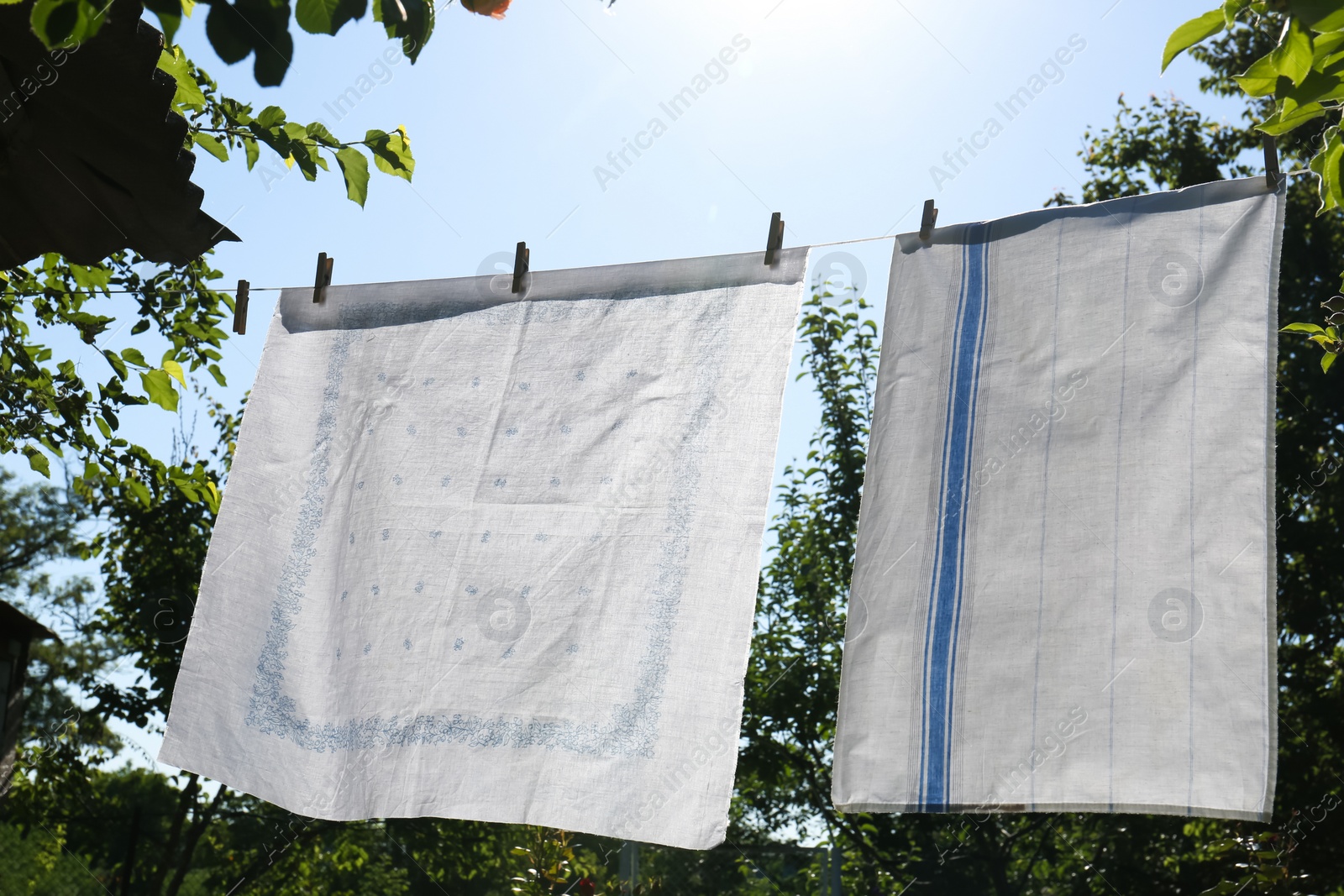 Photo of Washing line with clean laundry and clothespins outdoors