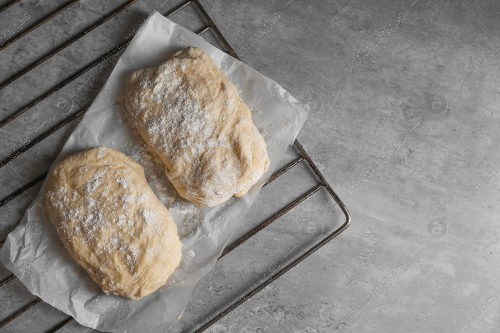 Photo of Raw dough and flour on grey table, top view with space for text. Cooking ciabatta