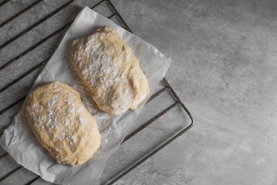 Photo of Raw dough and flour on grey table, top view with space for text. Cooking ciabatta