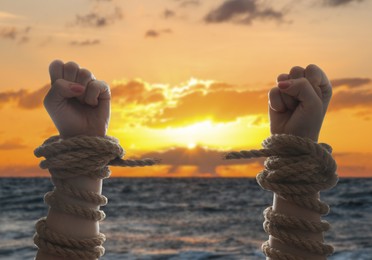 Image of Freedom. Woman with ripped ropes near sea at sunset, closeup