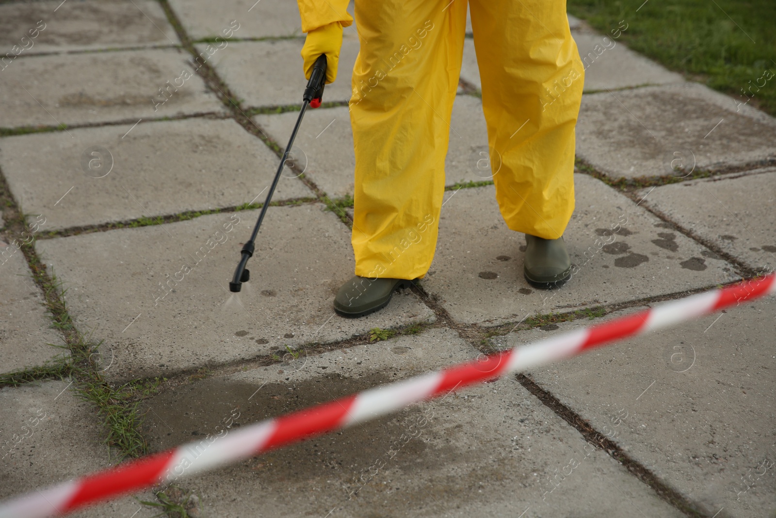 Photo of Person in hazmat suit disinfecting street pavement with sprayer, closeup. Surface treatment during coronavirus pandemic