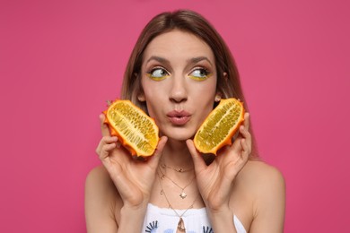 Young woman with fresh kiwano on pink background. Exotic fruit