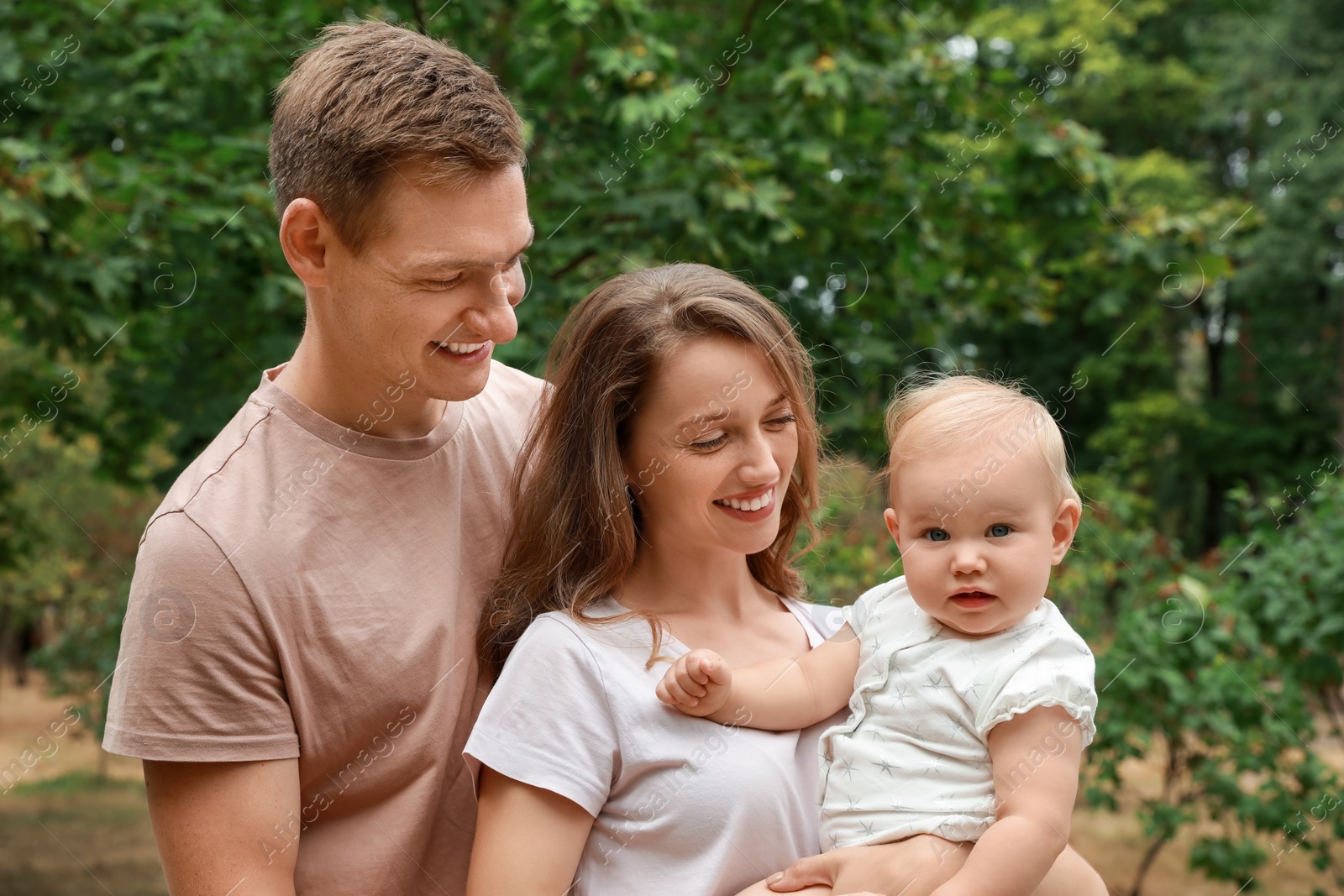 Photo of Parents with their cute baby spending time together outdoors. Happy family