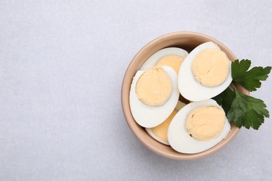 Photo of Fresh hard boiled eggs and parsley on light grey table, top view. Space for text