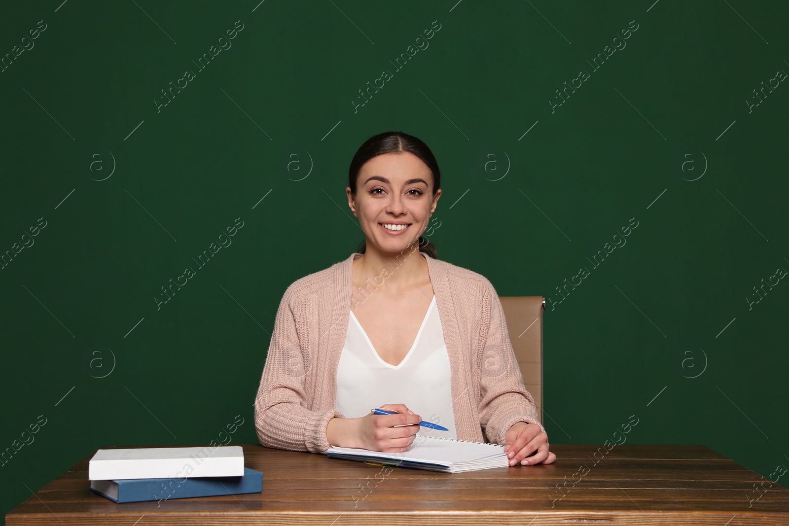 Photo of Portrait of young teacher at table against green background