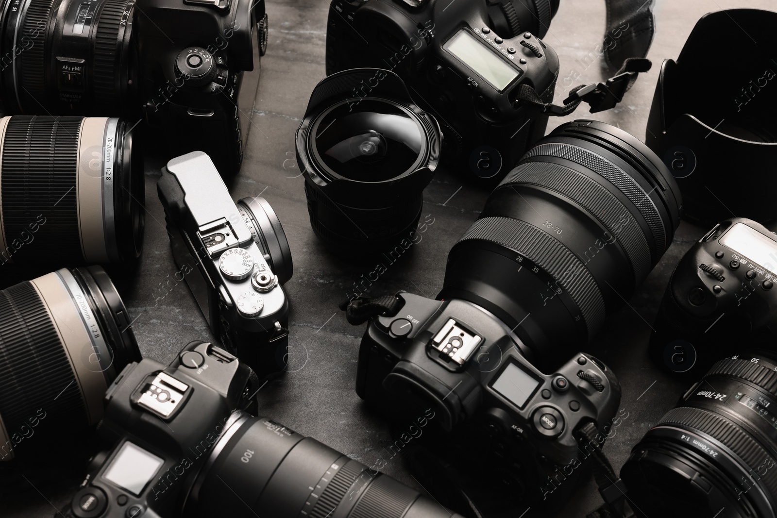 Photo of Modern cameras on dark gray table, closeup