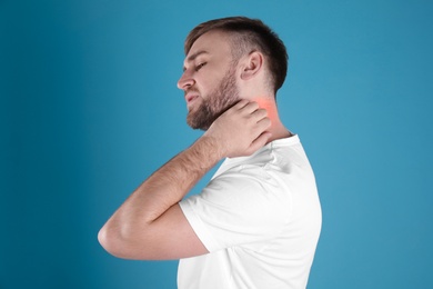 Photo of Man scratching neck on color background. Allergy symptoms