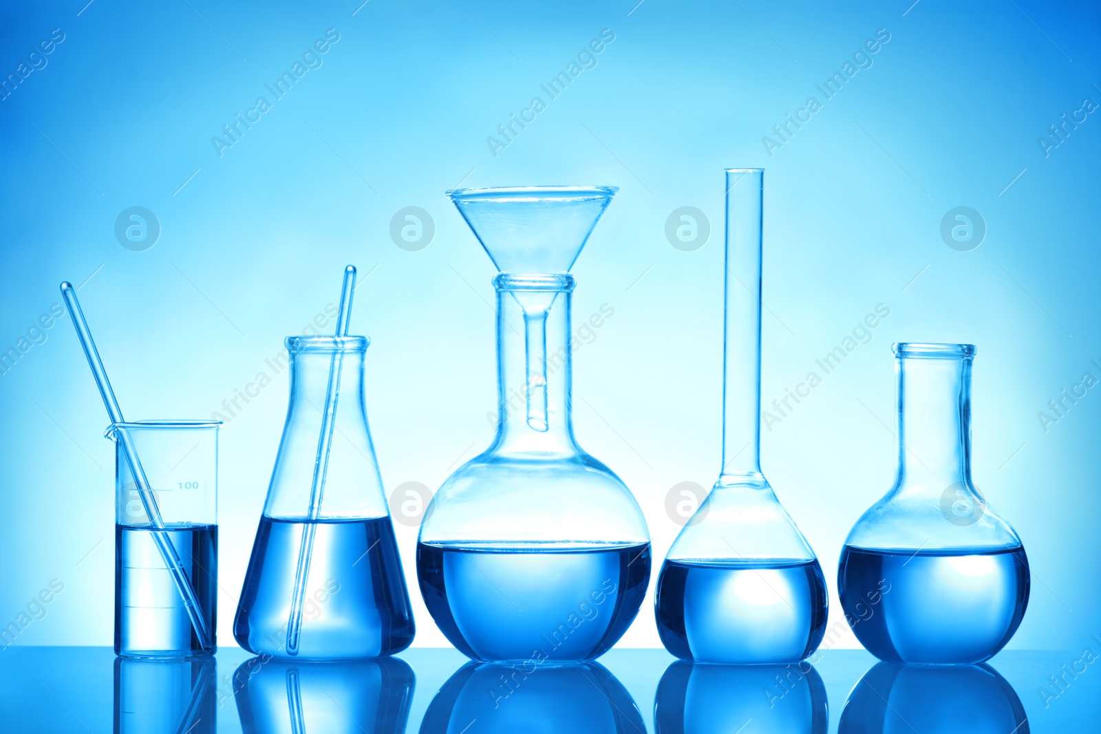 Photo of Laboratory glassware with liquid samples for analysis on blue background