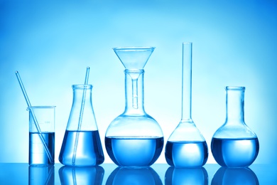Photo of Laboratory glassware with liquid samples for analysis on blue background