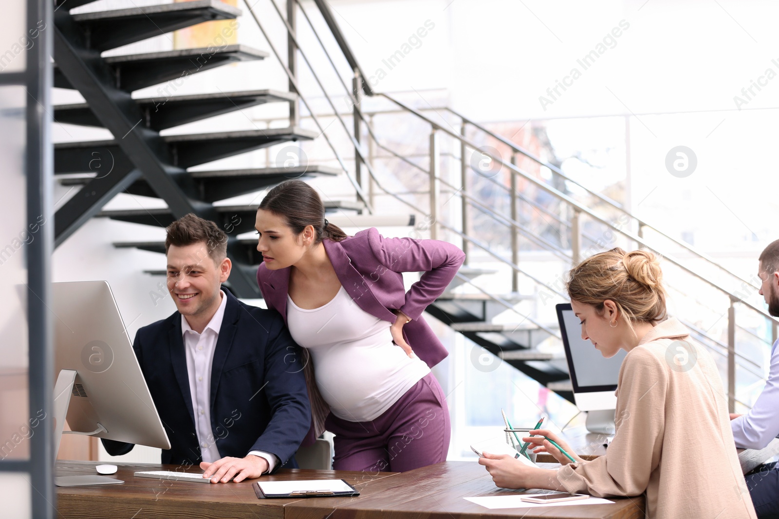 Photo of Young pregnant woman working with her employees in office