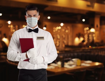 Image of Waiter in medical face mask in restaurant. Space for text