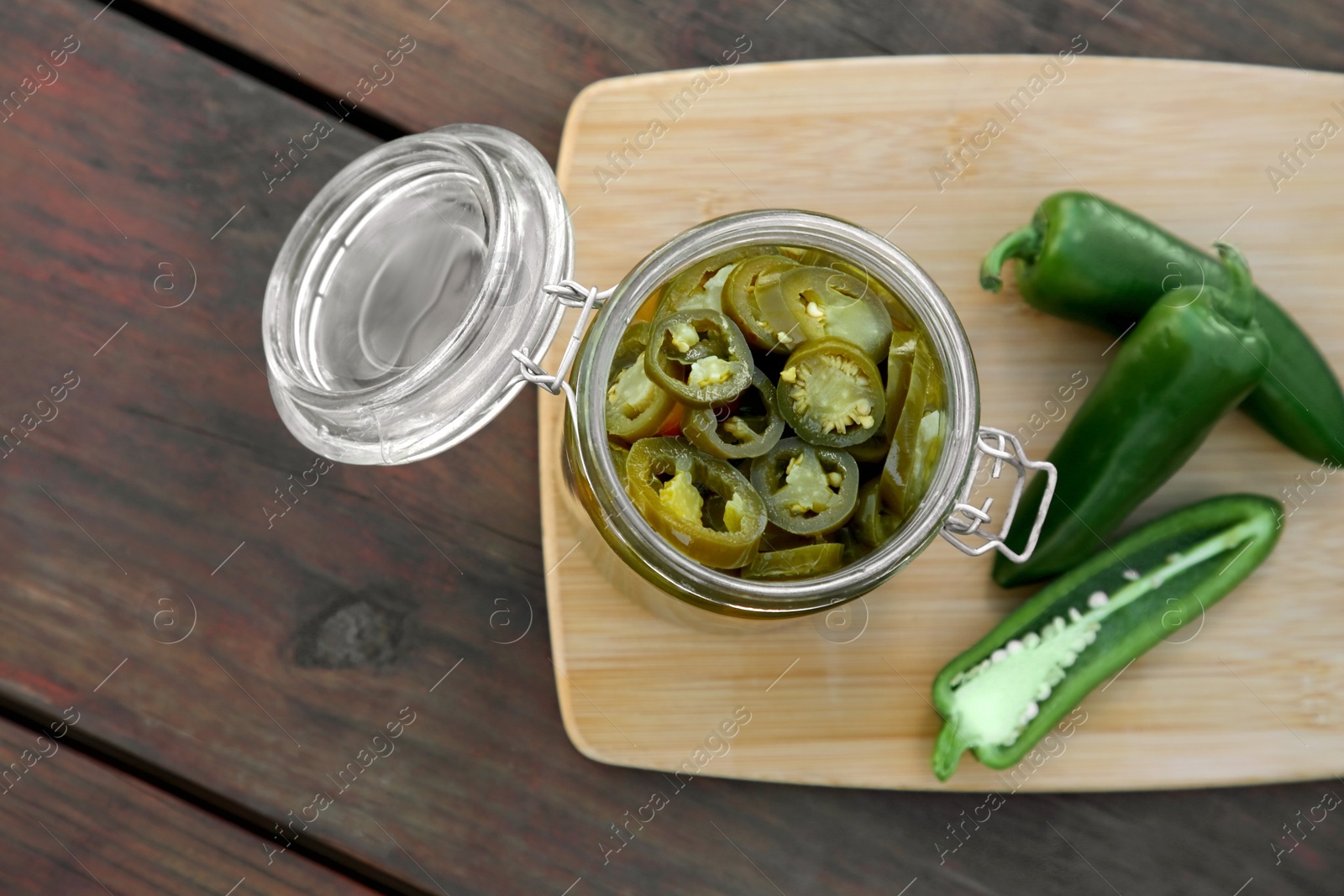 Photo of Fresh and pickled green jalapeno peppers on wooden table, top view