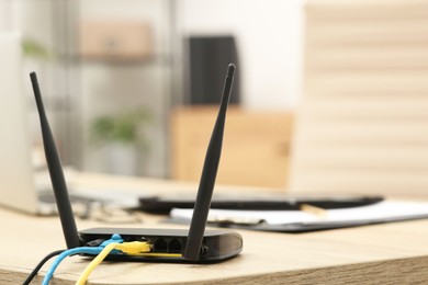 Photo of Modern Wi-Fi router on wooden table indoors, space for text