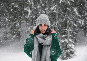 Young woman wearing warm clothes outdoors on snowy day. Winter vacation