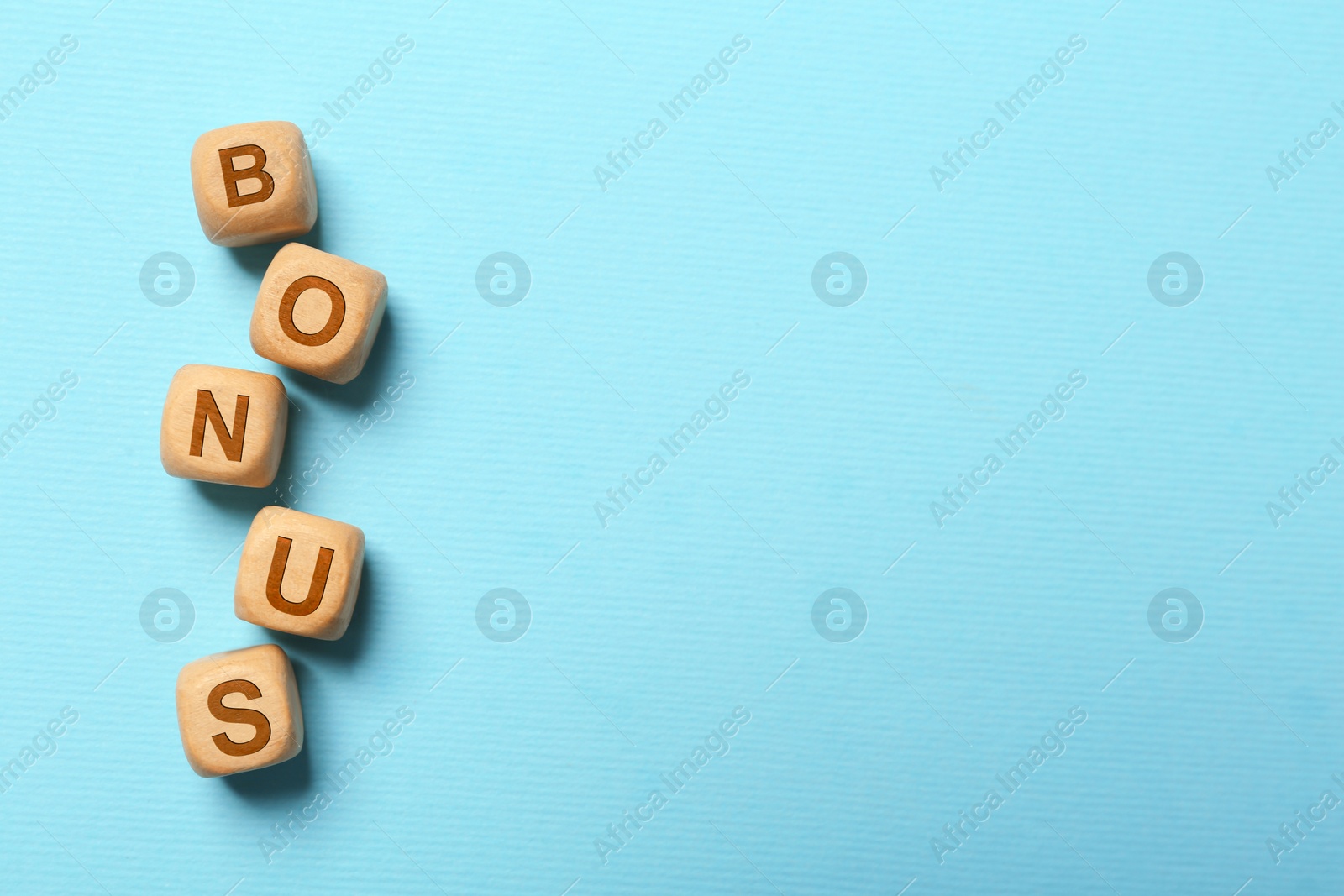 Image of Word Bonus made of color cubes with letters on light blue background, top view. Space for text