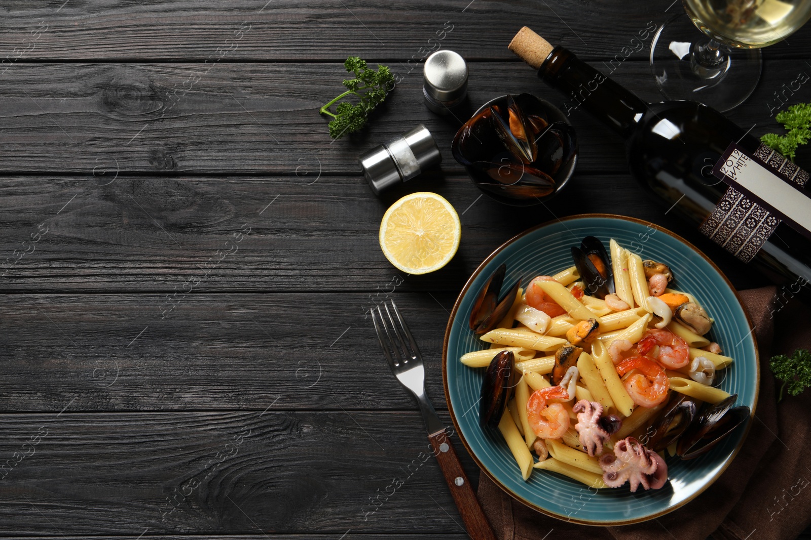 Photo of Delicious pasta with seafood served on black wooden table, flat lay. Space for text