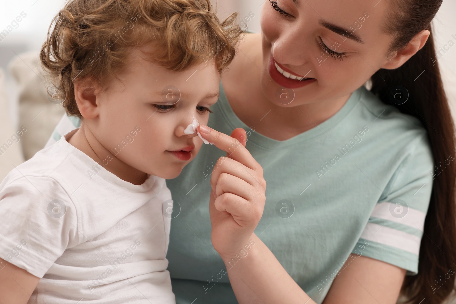 Photo of Mother applying ointment onto her son`s nose