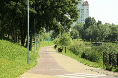 Photo of Quiet park with green trees and pathway on sunny day