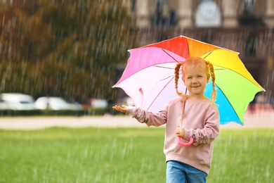 Photo of Cute little girl with bright umbrella in park