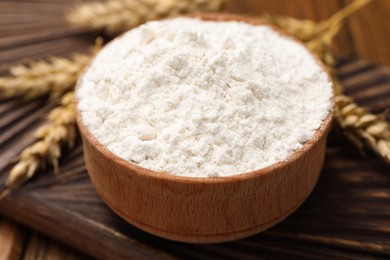 Photo of Bowl of organic wheat flour on wooden table, closeup