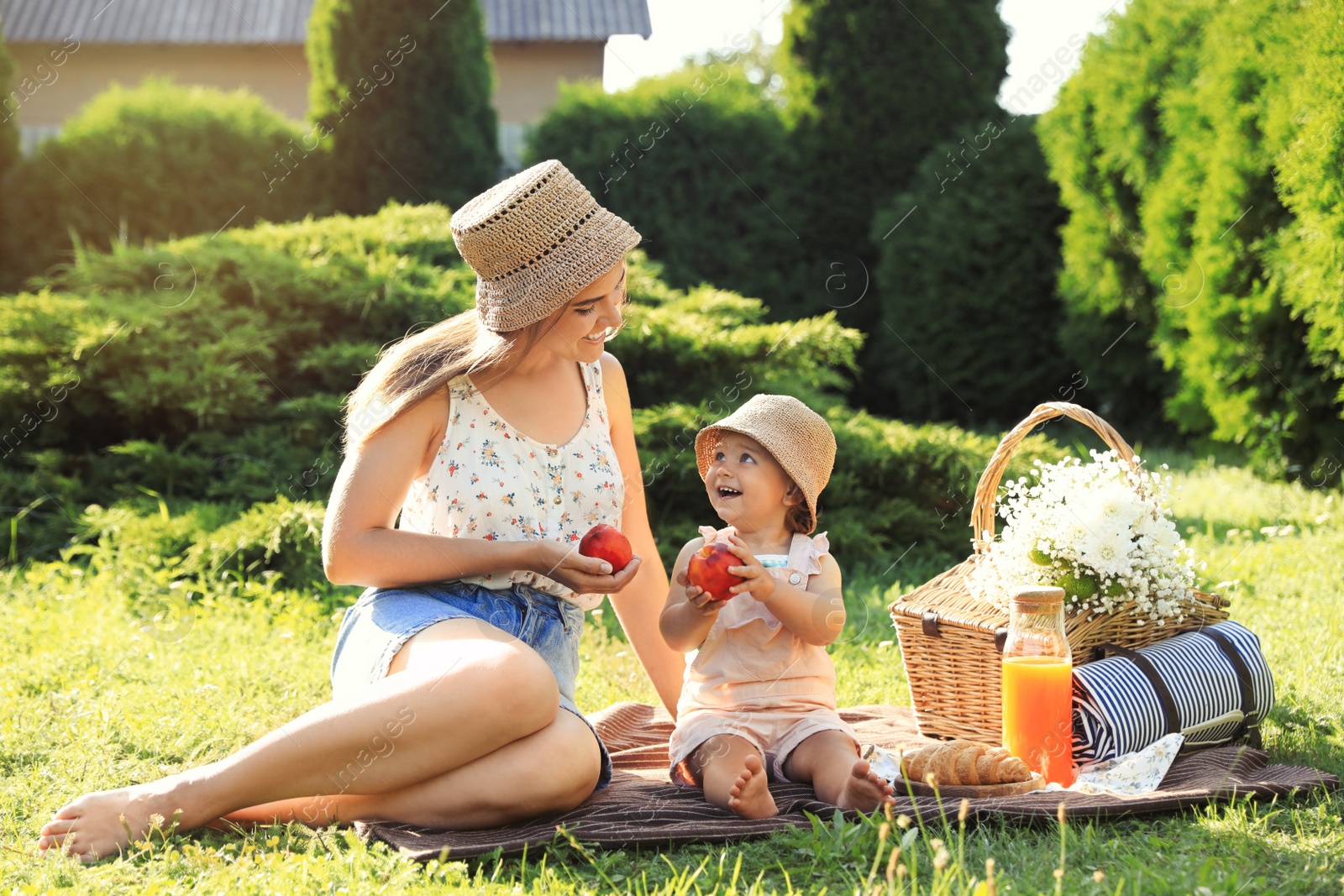 Photo of Mother with her baby daughter having picnic in garden on sunny day