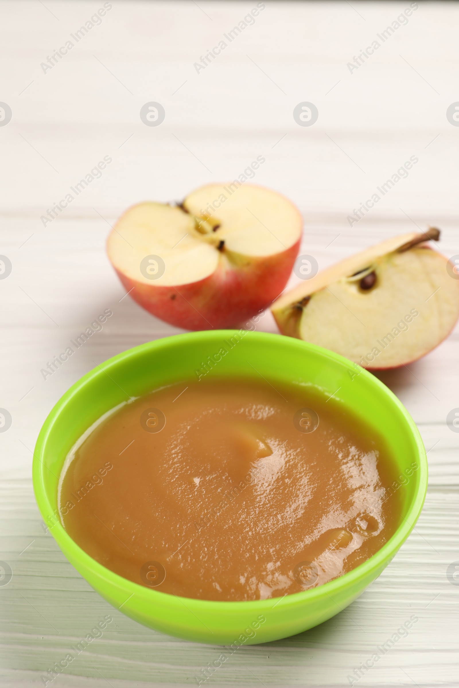 Photo of Baby food. Puree of apples in bowl on white wooden table