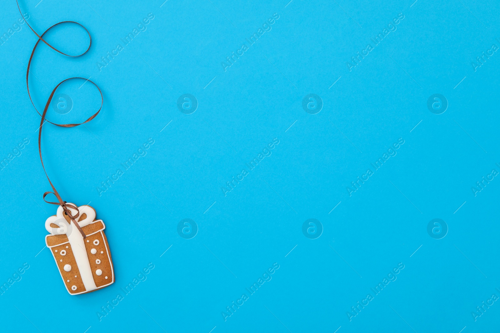 Photo of Gift box shaped Christmas cookie on light blue background, top view. Space for text