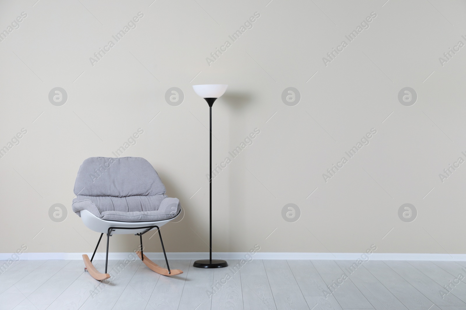 Photo of Rocking chair and lamp near color wall with space for text. Interior element