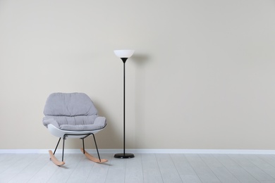 Rocking chair and lamp near color wall with space for text. Interior element