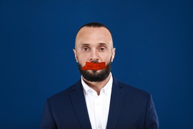 Image of Mature man with taped mouth on blue background. Speech censorship