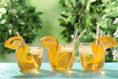 Delicious refreshing drink with orange and lime slices on light blue wooden table