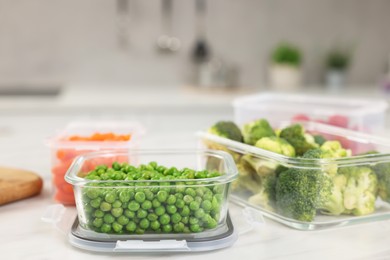 Containers with green peas and fresh products on white table, space for text. Food storage